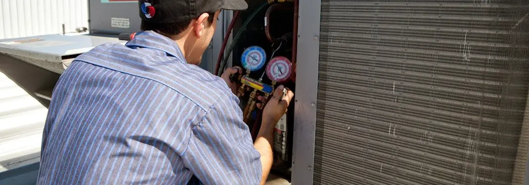 HVAC technician servicing a condenser unit in Perris