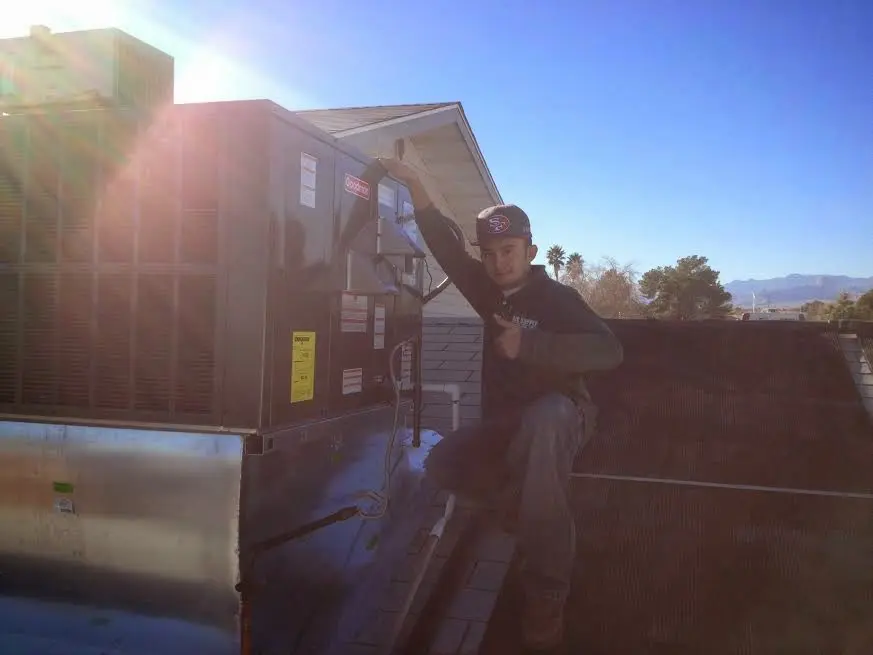 HVAC technician performing Air Duct Cleaning on a rooftop unit in Perris